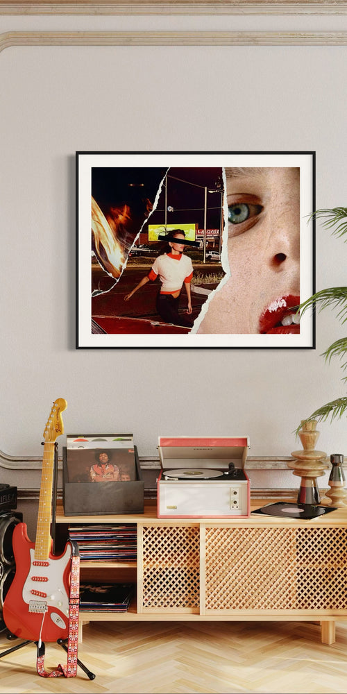 Framed artwork on a wall above a wooden console table with records and a guitar.