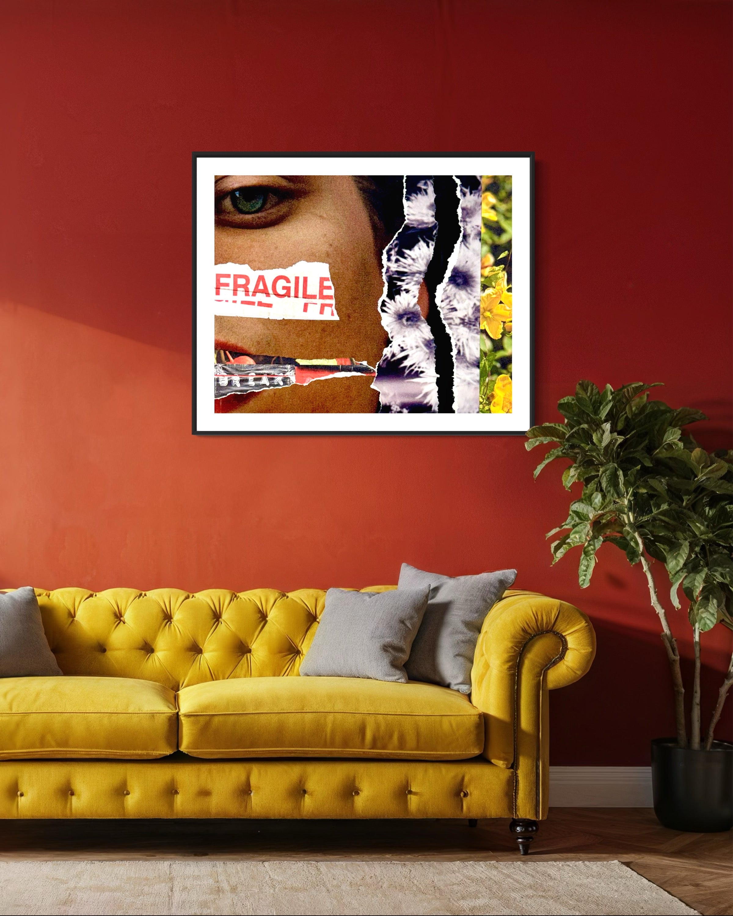 Yellow sofa with gray cushions in a room with a red wall and a framed artwork.