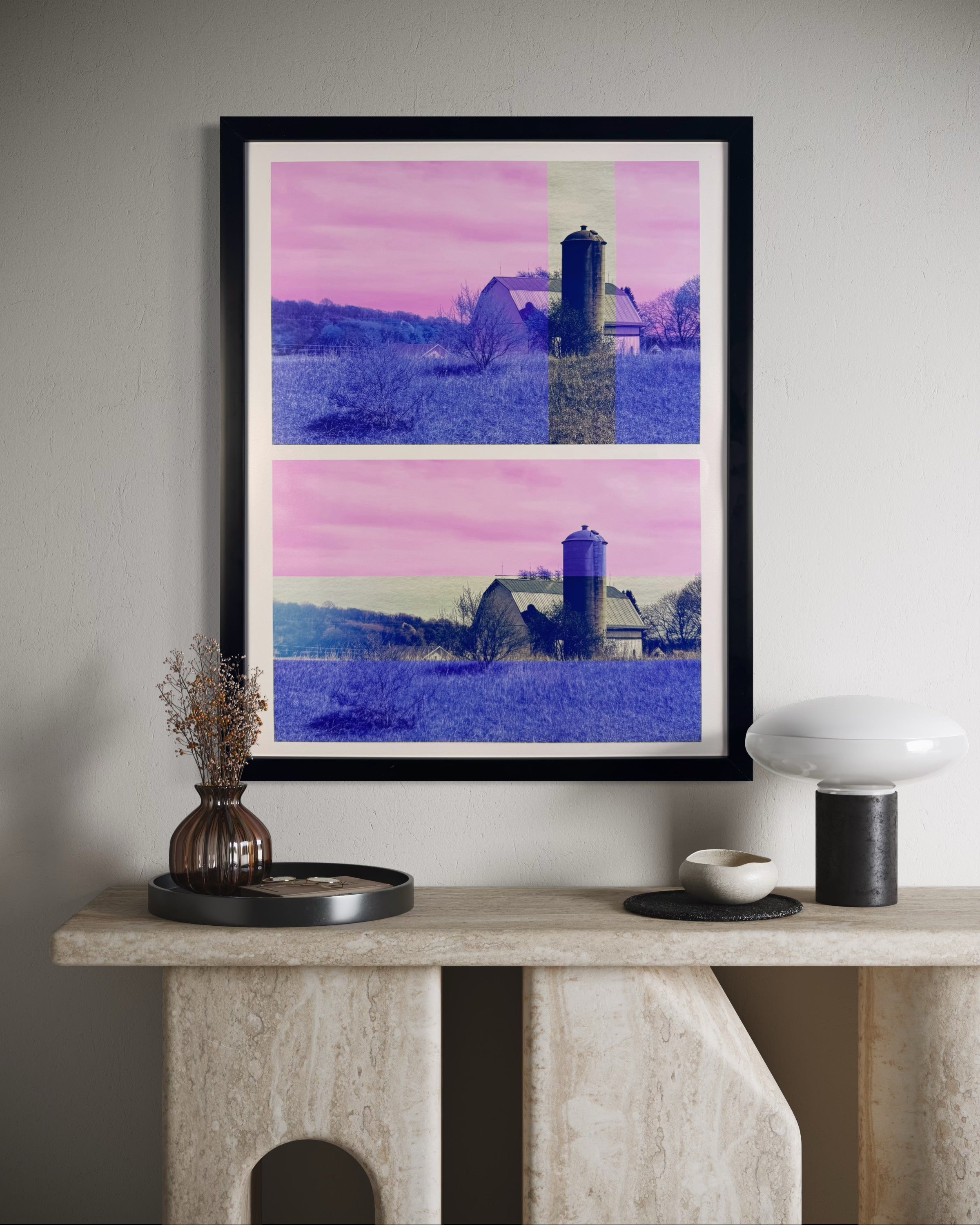 Framed artwork of a barn and silo on a wall above a console table.