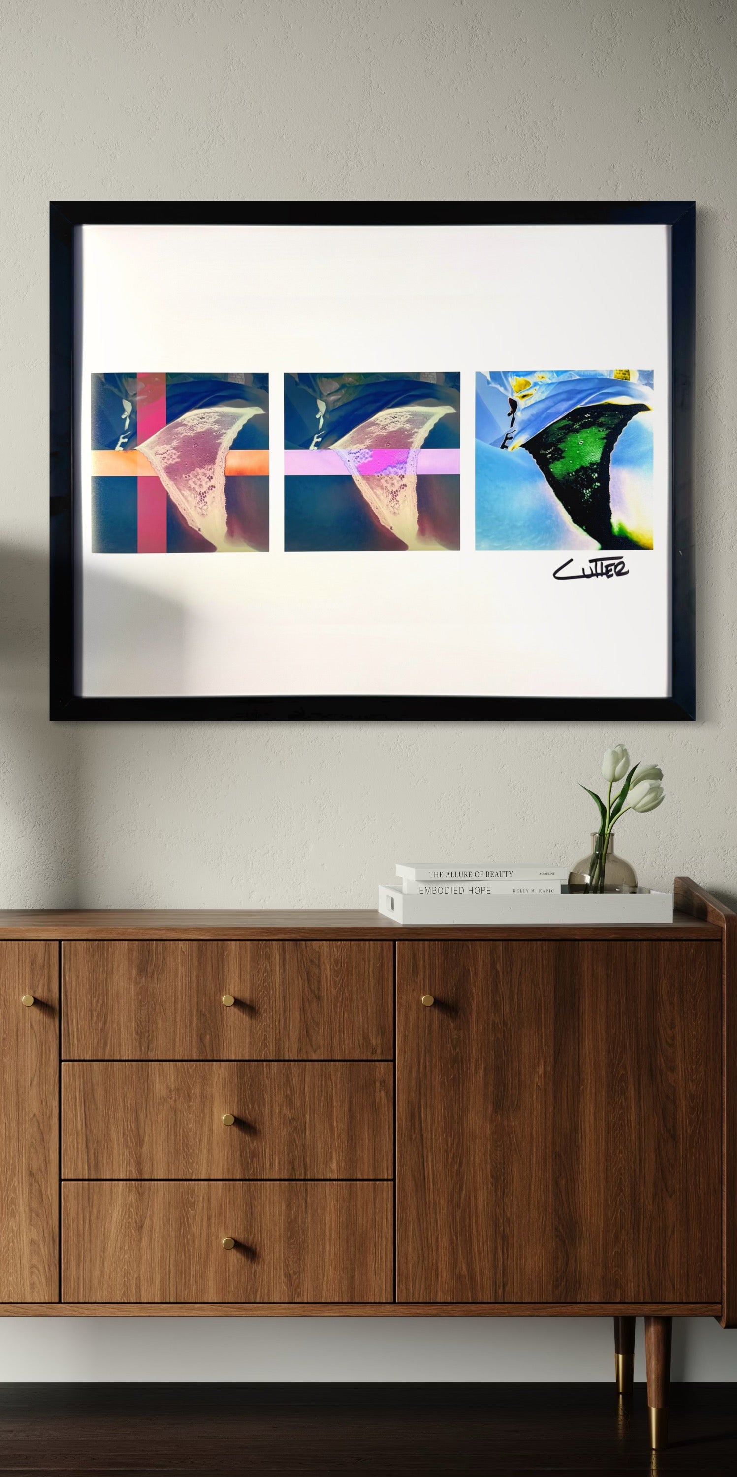 Framed abstract artwork on a wall above a wooden cabinet